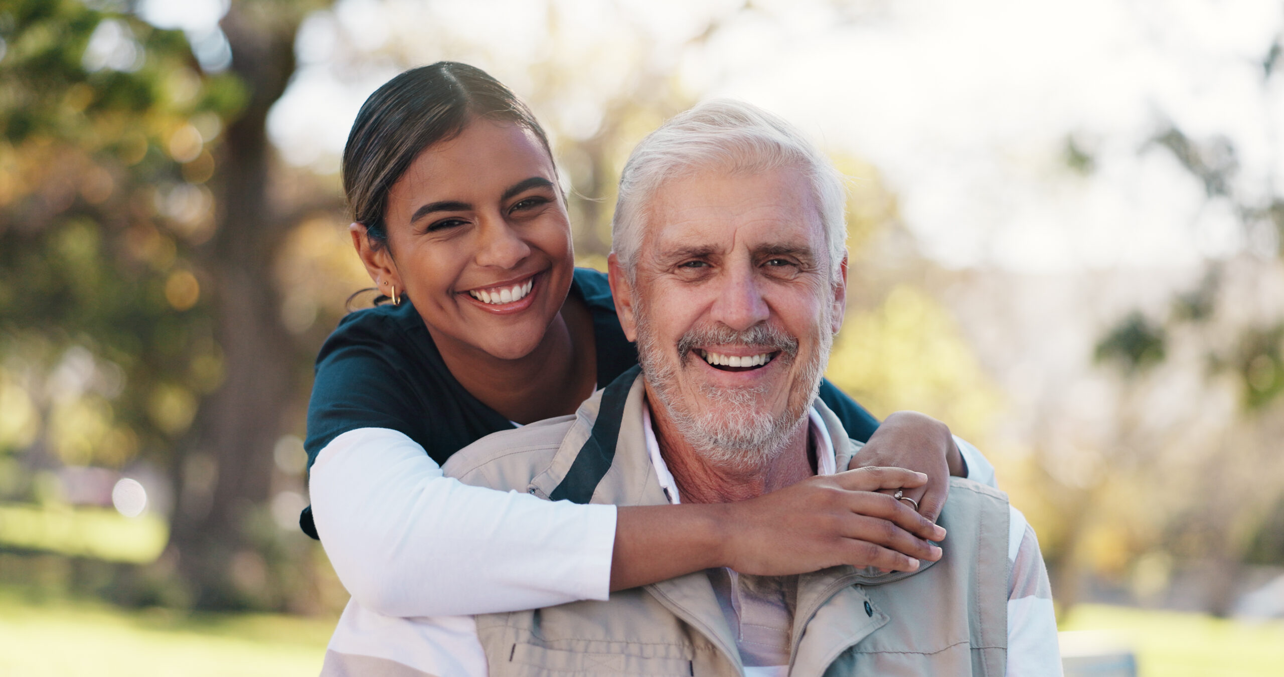 Hug, portrait and smile of nurse with old man in park for assisted living or rehabilitation. Love, retirement or wellness with happy caregiver and senior patient embracing in nature for support Carer spending time with a patient